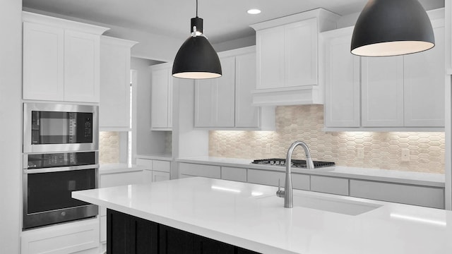 kitchen with stainless steel appliances, white cabinetry, pendant lighting, and decorative backsplash