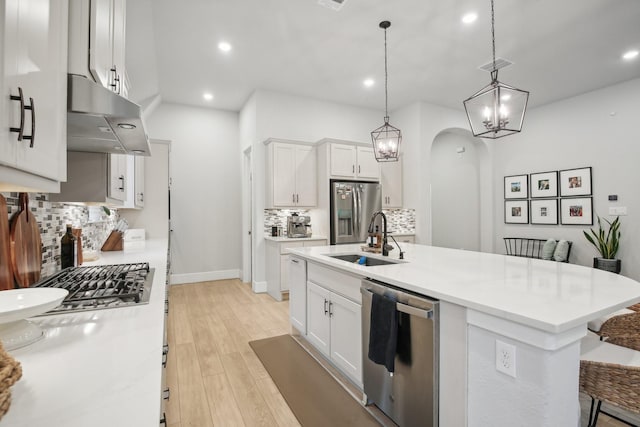 kitchen featuring a kitchen island with sink, ventilation hood, white cabinets, sink, and stainless steel appliances