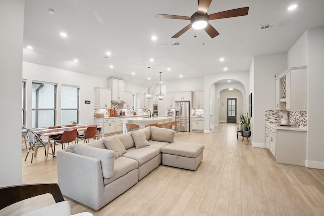 living room with ceiling fan, sink, and light hardwood / wood-style flooring