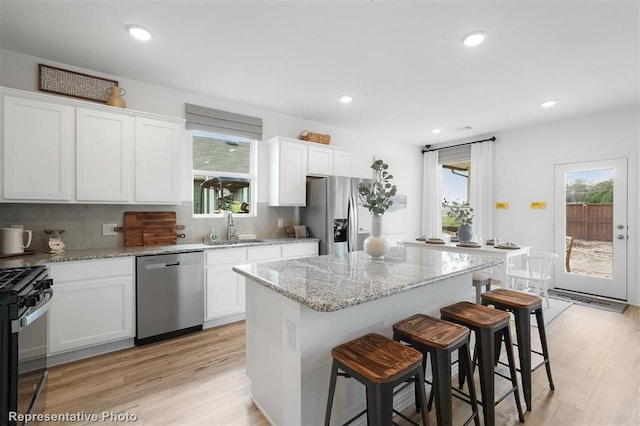 kitchen featuring plenty of natural light, white cabinetry, a center island, and stainless steel appliances