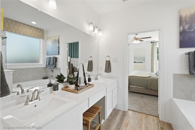 bathroom with a washtub, vanity, hardwood / wood-style flooring, and ceiling fan