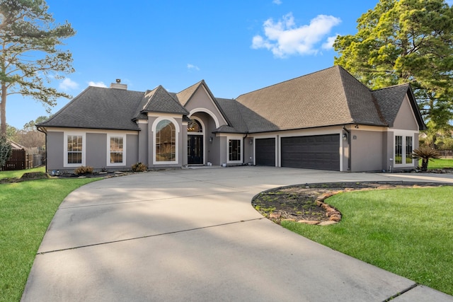 french country home featuring a garage and a front lawn