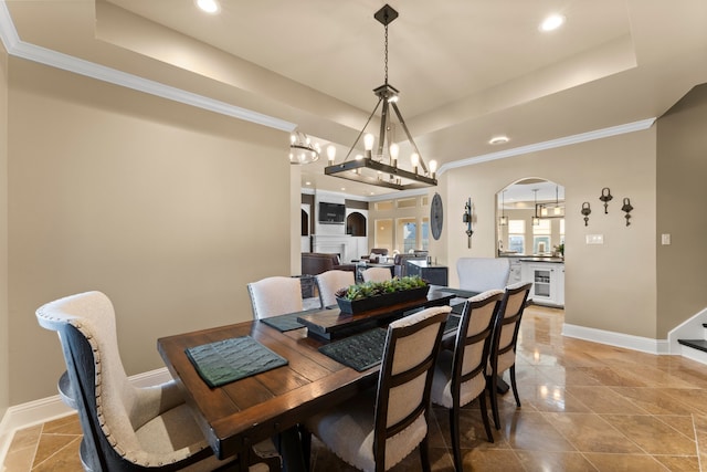 dining room with a chandelier, beverage cooler, a raised ceiling, and ornamental molding