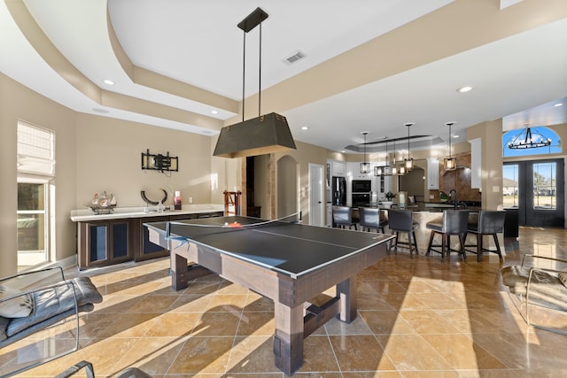 playroom featuring a tray ceiling, a chandelier, and sink