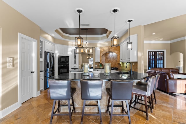 kitchen with sink, black appliances, tasteful backsplash, white cabinets, and pendant lighting