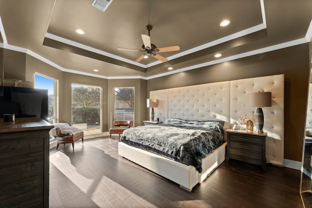 bedroom with dark wood-type flooring, ceiling fan, ornamental molding, and a tray ceiling