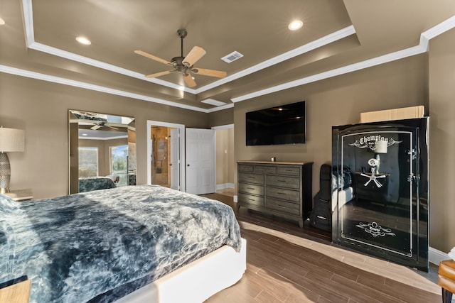 bedroom with hardwood / wood-style floors, ceiling fan, ornamental molding, and a tray ceiling