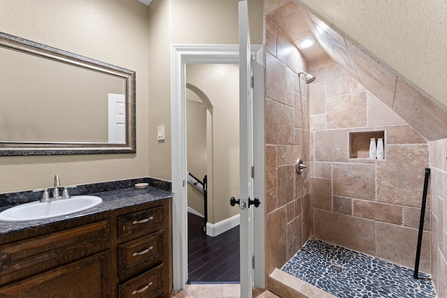 bathroom featuring tiled shower, vanity, and wood-type flooring