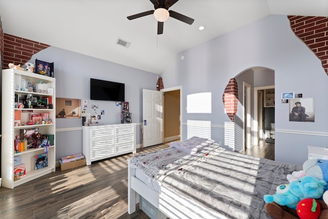 bedroom with ceiling fan, dark hardwood / wood-style floors, brick wall, and lofted ceiling