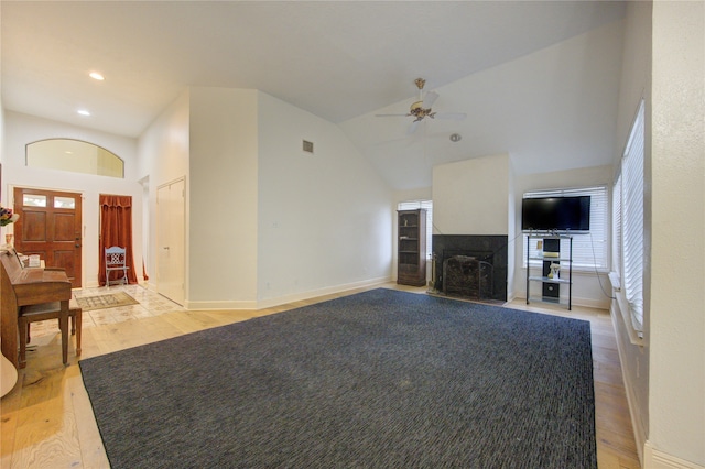 unfurnished living room with a multi sided fireplace, light hardwood / wood-style floors, ceiling fan, and high vaulted ceiling