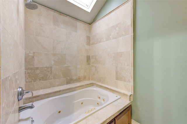 bathroom with tiled shower / bath and vaulted ceiling with skylight