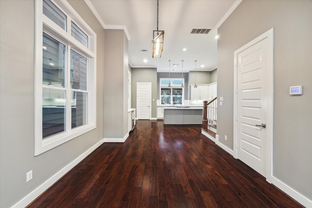 kitchen with a center island, white cabinetry, ornamental molding, pendant lighting, and dark wood-type flooring