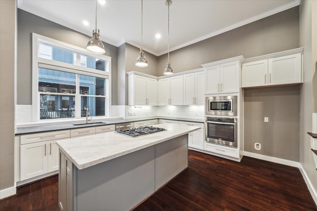 kitchen featuring light stone countertops, white cabinets, appliances with stainless steel finishes, sink, and hanging light fixtures