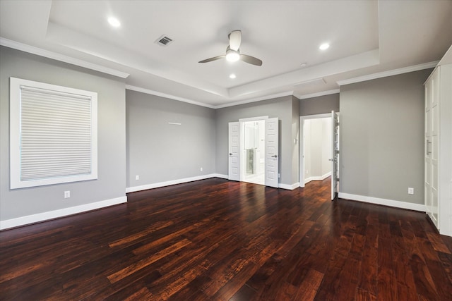 empty room featuring ornamental molding, dark wood-type flooring, ceiling fan, and a raised ceiling