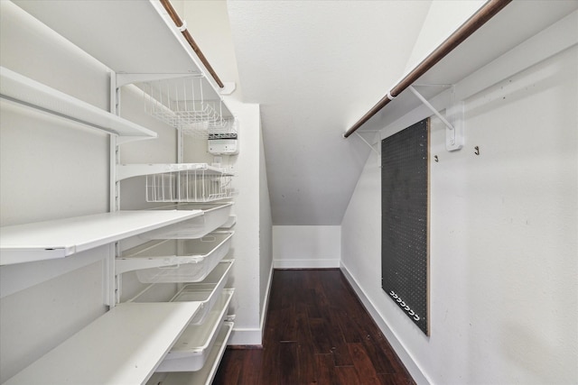 spacious closet with dark wood-type flooring and lofted ceiling