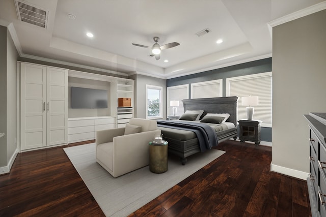 bedroom with dark wood-type flooring, a wood stove, ornamental molding, a raised ceiling, and ceiling fan