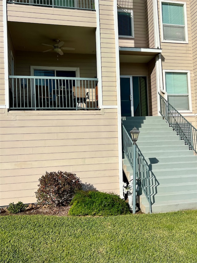 entrance to property featuring a lawn and ceiling fan