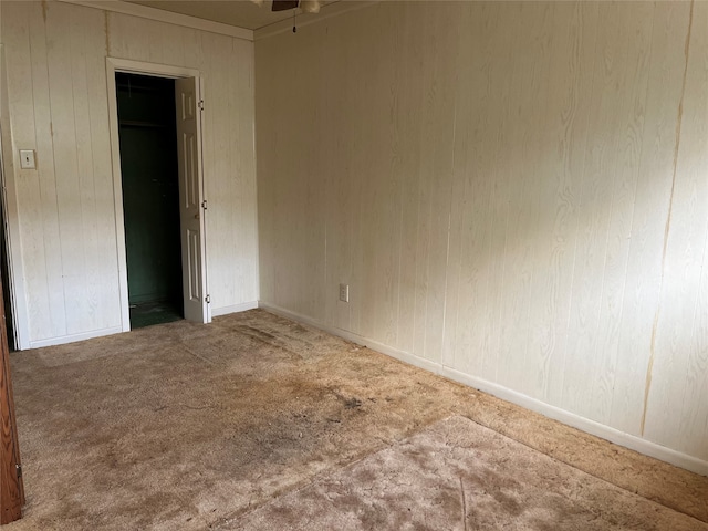 spare room featuring carpet and wood walls