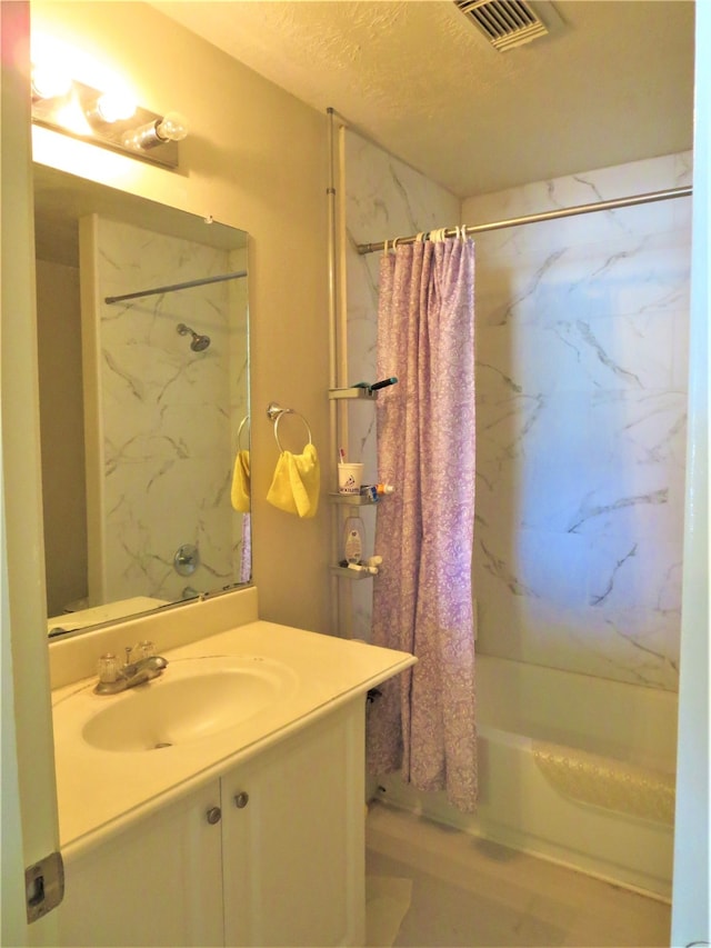 bathroom featuring shower / bath combination with curtain, vanity, and a textured ceiling