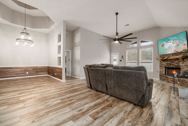 living room featuring ceiling fan, vaulted ceiling, a fireplace, and light hardwood / wood-style flooring