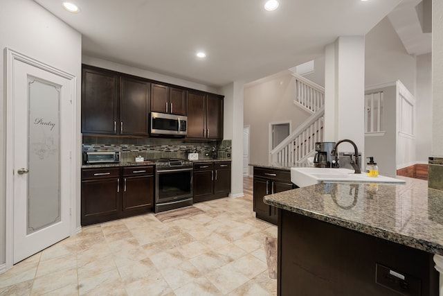 kitchen featuring decorative backsplash, appliances with stainless steel finishes, dark stone counters, dark brown cabinetry, and sink