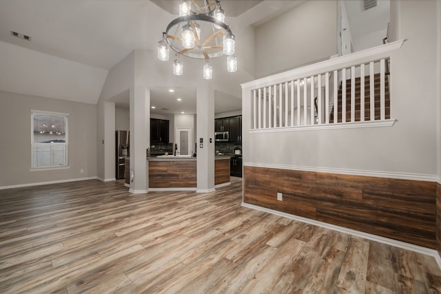 unfurnished dining area featuring light wood-type flooring, high vaulted ceiling, and sink