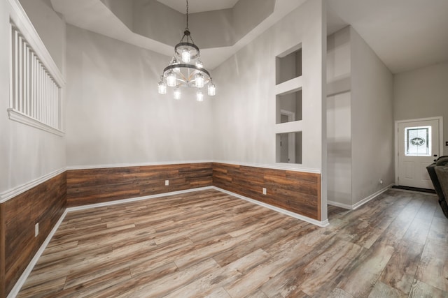 spare room featuring wood walls, built in features, a high ceiling, and hardwood / wood-style flooring