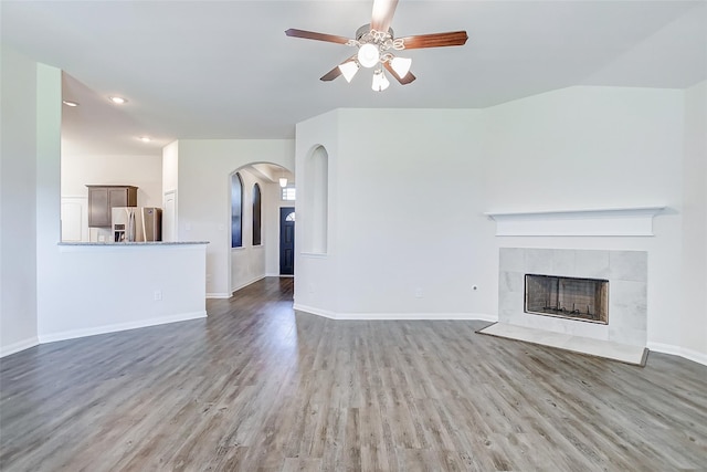 unfurnished living room featuring hardwood / wood-style floors, lofted ceiling, a fireplace, and ceiling fan