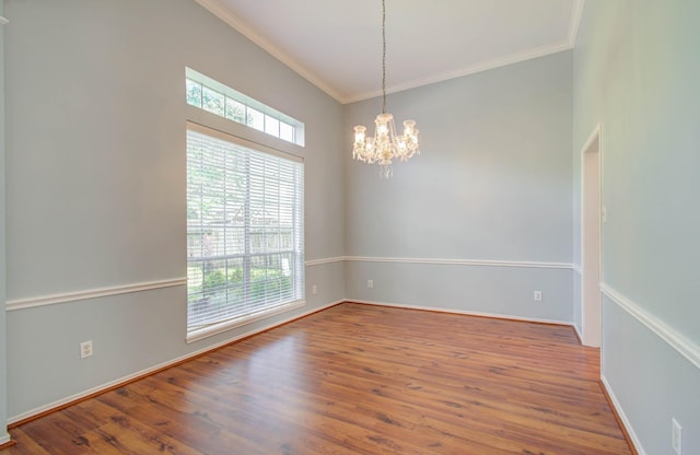 spare room featuring hardwood / wood-style flooring, ornamental molding, and a chandelier