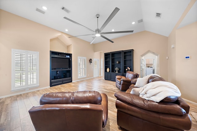 living room featuring light wood-type flooring, lofted ceiling, ceiling fan, and washer / dryer