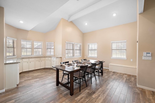 dining area with hardwood / wood-style flooring, beam ceiling, and high vaulted ceiling