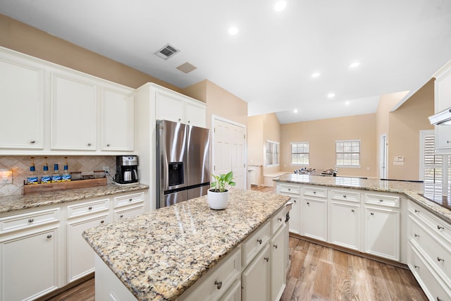 kitchen with white cabinets, light wood-type flooring, plenty of natural light, and stainless steel fridge with ice dispenser