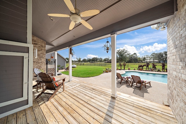 wooden terrace with a lawn, ceiling fan, a fenced in pool, and a patio area