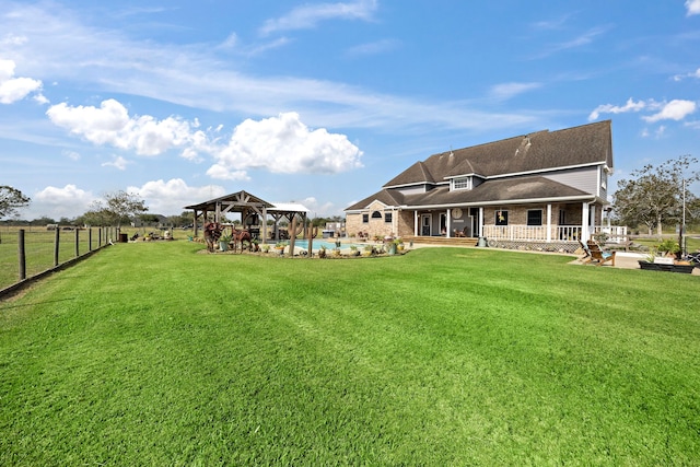 rear view of property featuring a gazebo, a patio, a yard, and a pool