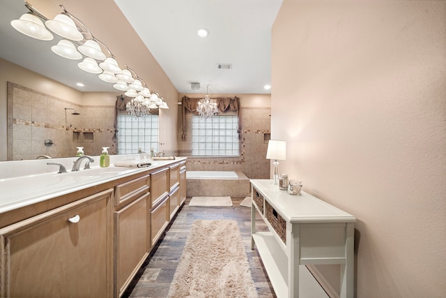 bathroom with an inviting chandelier, vanity, wood-type flooring, and separate shower and tub