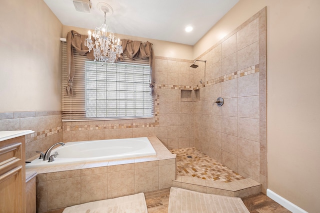 bathroom with independent shower and bath, vanity, and an inviting chandelier