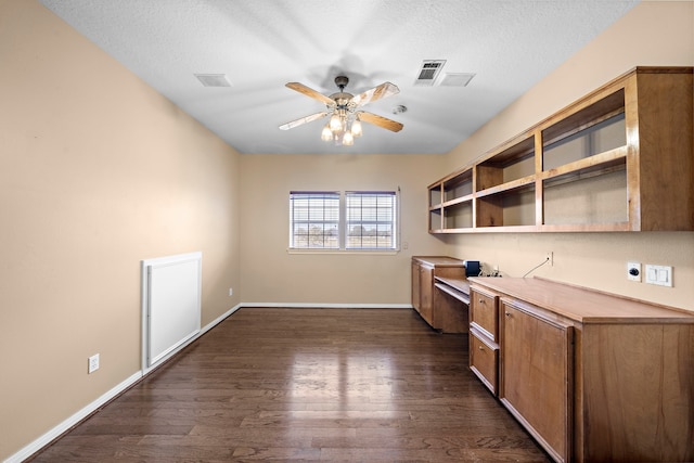 kitchen featuring ceiling fan, built in desk, dark hardwood / wood-style floors, and a textured ceiling