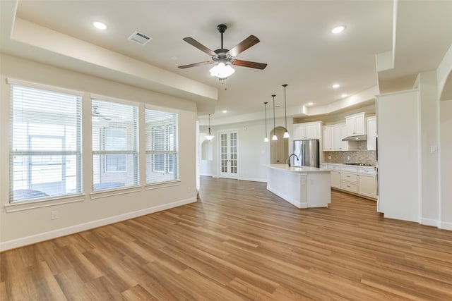 kitchen featuring stainless steel appliances, a wealth of natural light, an island with sink, and light wood-type flooring