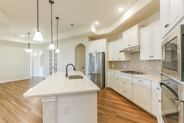 kitchen with stainless steel appliances, a center island with sink, light hardwood / wood-style flooring, and white cabinets