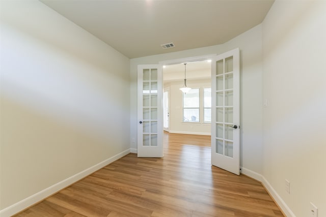 spare room featuring french doors and light hardwood / wood-style floors