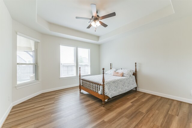 bedroom featuring a raised ceiling, hardwood / wood-style flooring, and ceiling fan