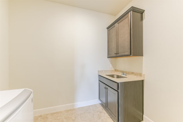 clothes washing area featuring cabinets, sink, and light tile patterned floors