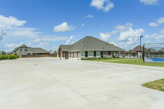 exterior space with tennis court and a yard