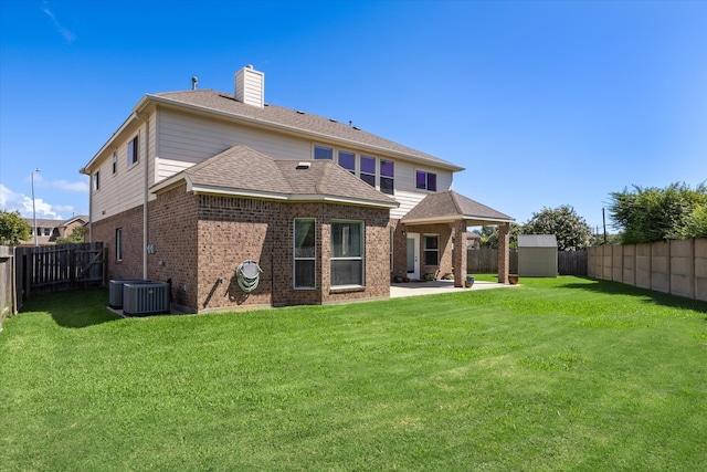 back of house featuring central AC unit, a patio area, a yard, and a shed