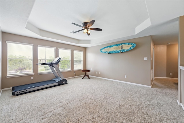 exercise area with ceiling fan, carpet, and a tray ceiling