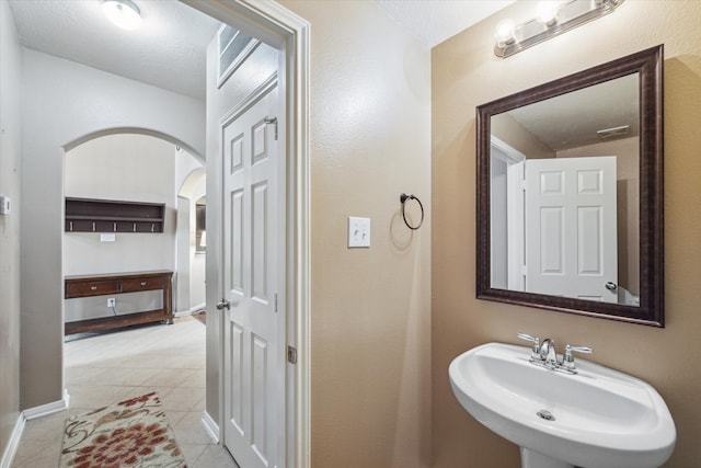 bathroom with a textured ceiling, sink, and tile patterned floors