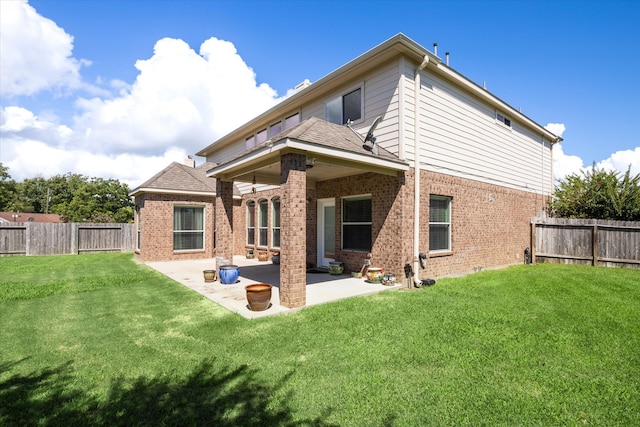 rear view of house featuring a lawn and a patio