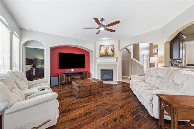 living room with a healthy amount of sunlight, a tiled fireplace, dark hardwood / wood-style floors, and ceiling fan