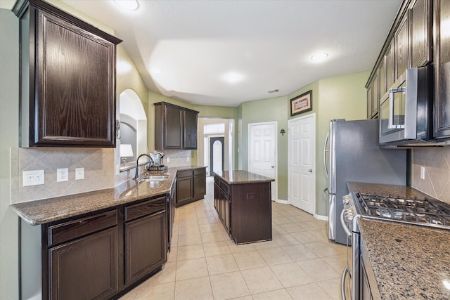 kitchen featuring dark stone countertops, appliances with stainless steel finishes, sink, and a center island