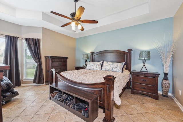 tiled bedroom with ceiling fan and a tray ceiling